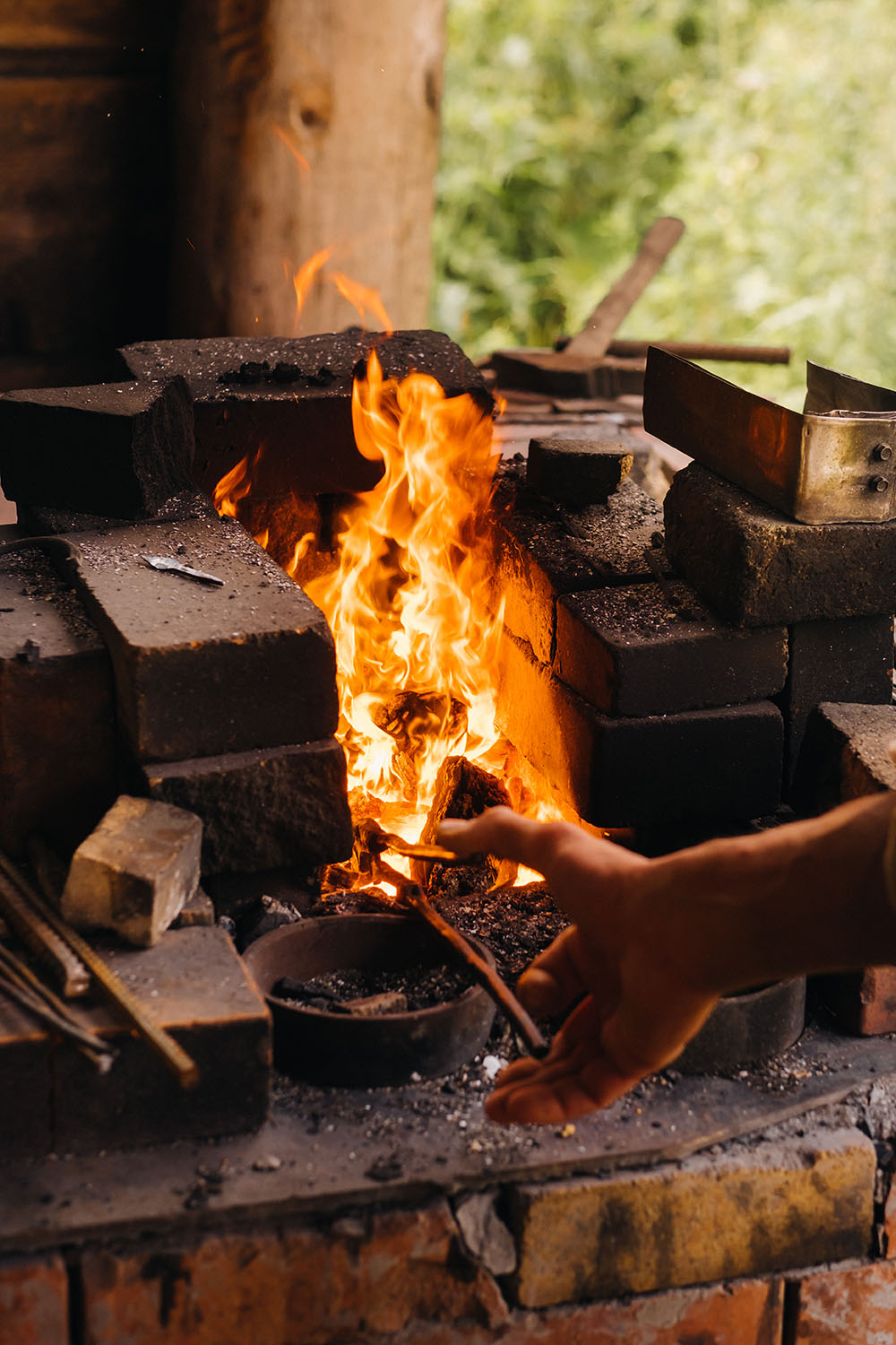 A blacksmith hardens steel at high temperature in a homemade furnace in the village.